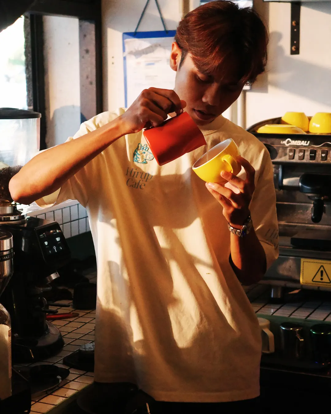 A Hirup barista pouring milk into a cup